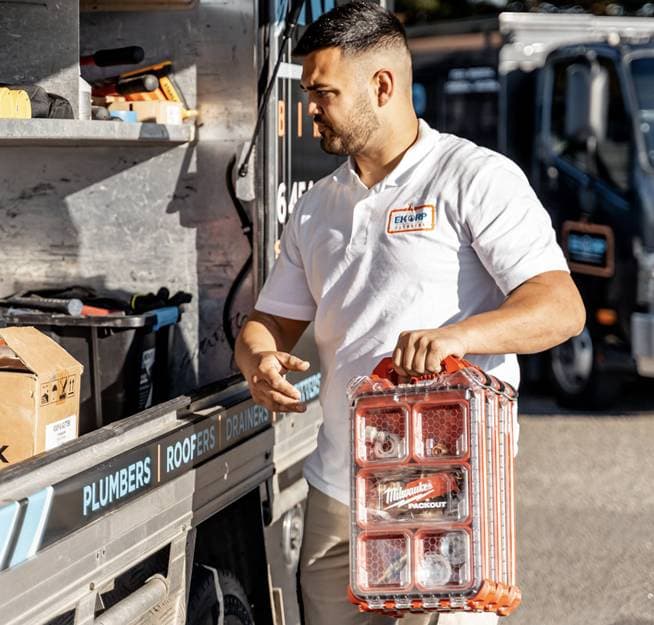A plumber carrying a case of plumbing fittings